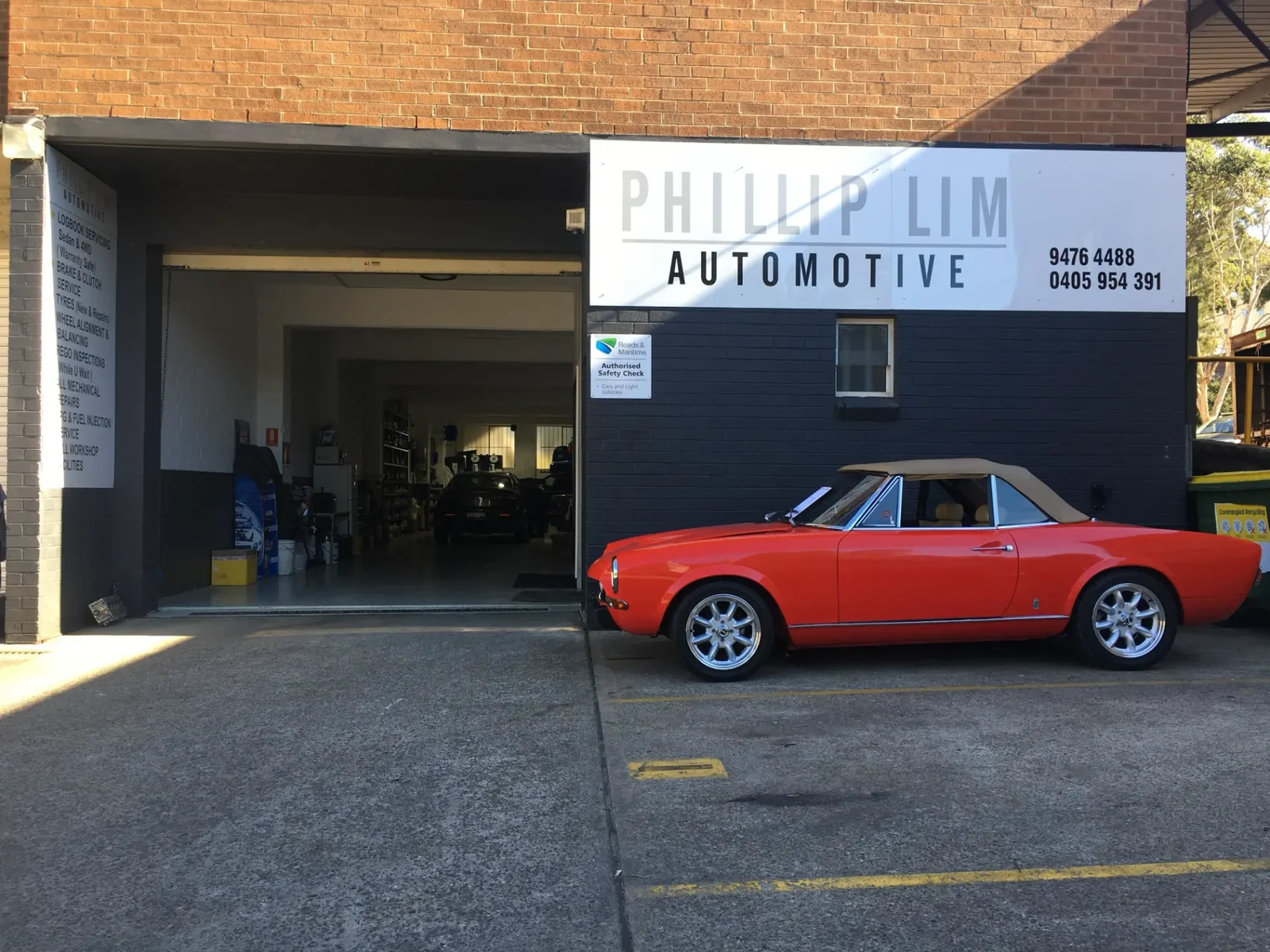 Phillip Lim Automotive shopfront at 1/1 Leighton Place, Hornsby, with a classic red convertible parked out front